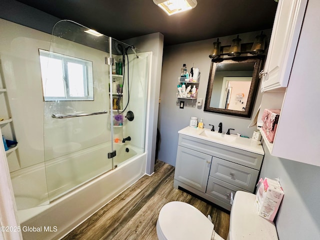 bathroom with toilet, combined bath / shower with glass door, wood finished floors, and vanity