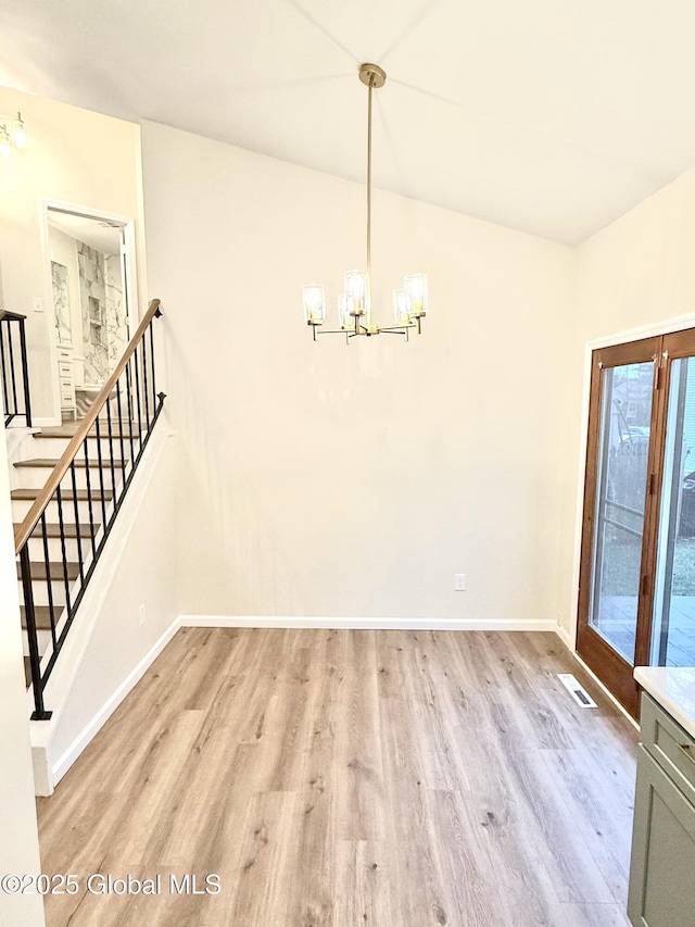 unfurnished dining area with light wood-style flooring, visible vents, stairway, and a notable chandelier