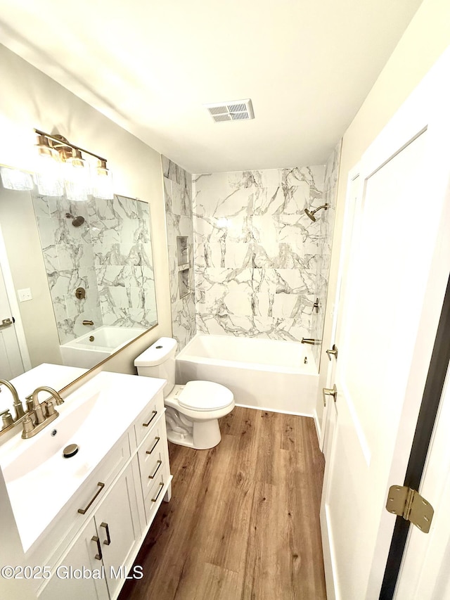 full bathroom with vanity, toilet, visible vents,  shower combination, and wood finished floors