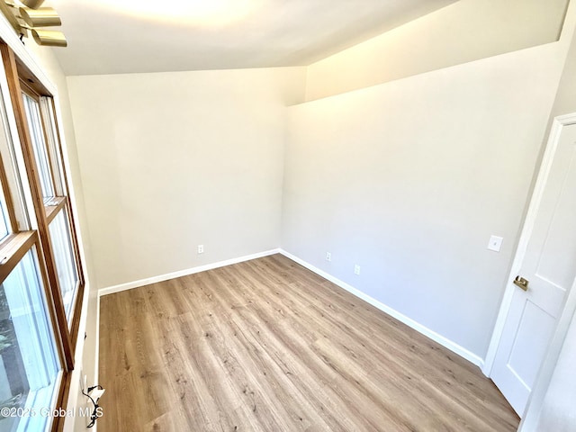 spare room with baseboards and light wood-type flooring