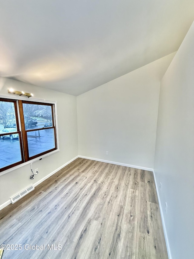 spare room featuring baseboards, visible vents, and wood finished floors