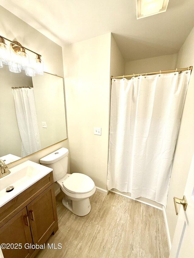 full bath featuring vanity, toilet, baseboards, curtained shower, and wood finished floors