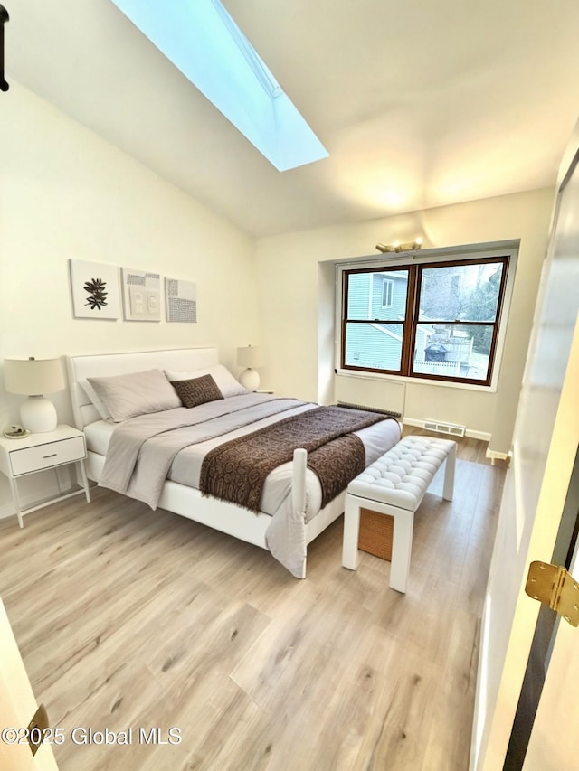 bedroom featuring lofted ceiling with skylight, visible vents, and wood finished floors