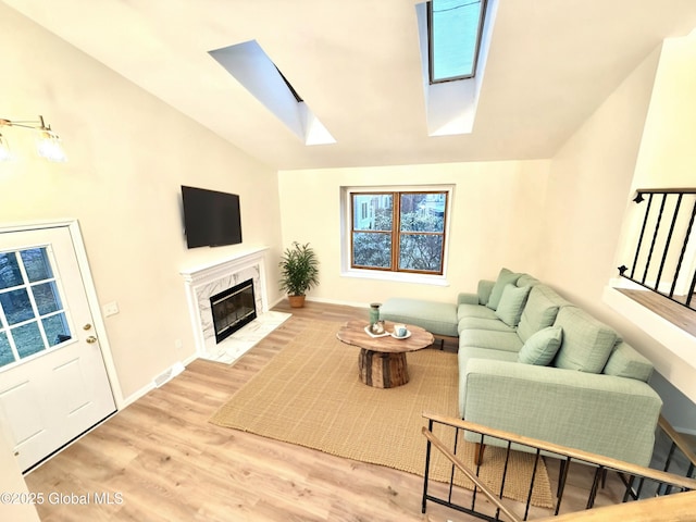 living room featuring baseboards, a fireplace, wood finished floors, and lofted ceiling with skylight