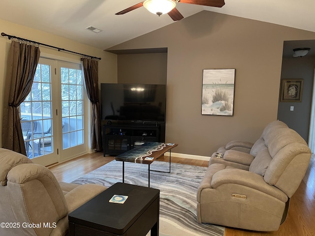 living room featuring lofted ceiling, visible vents, a ceiling fan, and wood finished floors