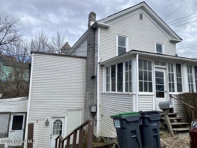 view of property exterior featuring a chimney, entry steps, and a sunroom