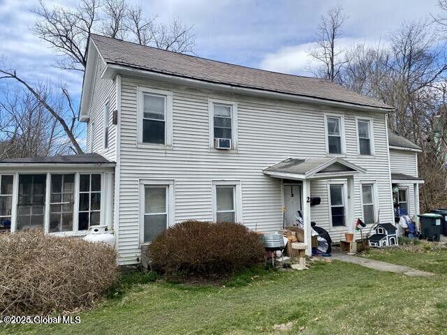 view of front of house featuring a sunroom, a shingled roof, and a front lawn