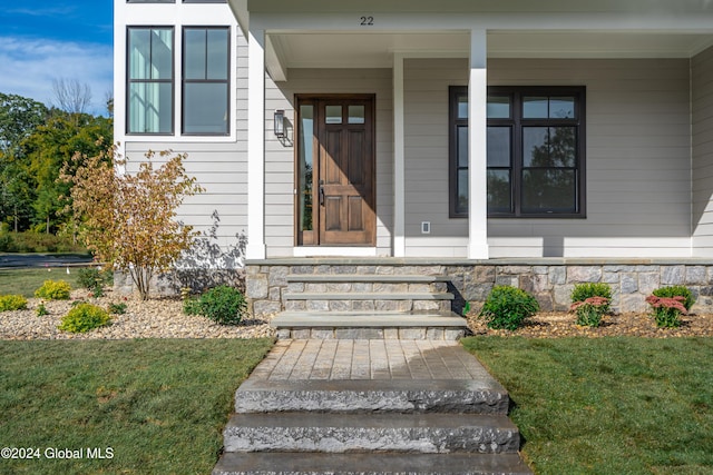 entrance to property featuring stone siding and a yard
