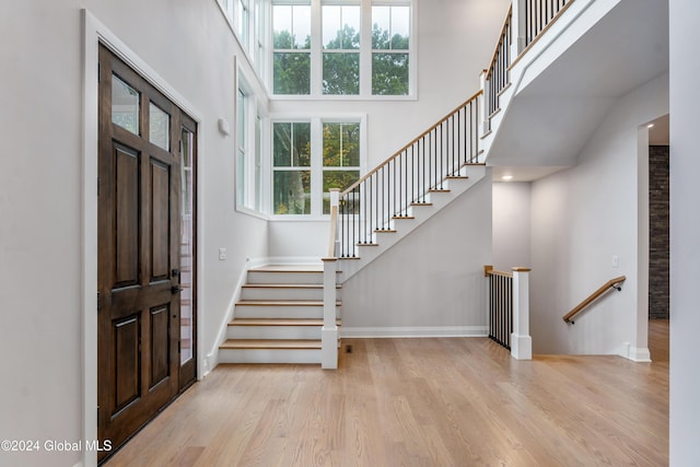 entrance foyer featuring baseboards, a high ceiling, wood finished floors, and stairs