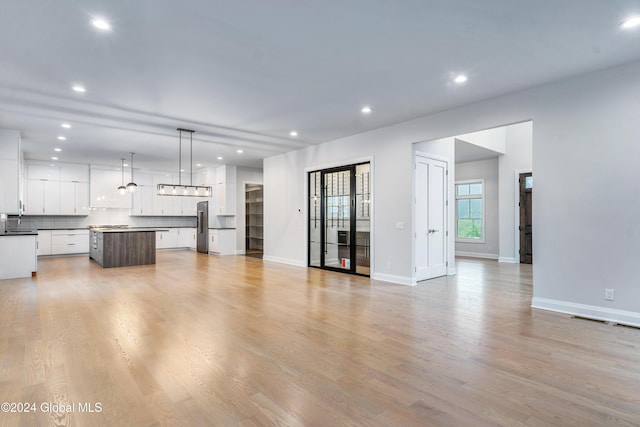 unfurnished living room featuring light wood finished floors, baseboards, visible vents, and recessed lighting