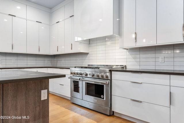 kitchen featuring white cabinets, dark countertops, light wood finished floors, and double oven range