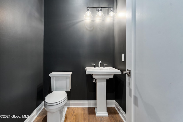 bathroom featuring toilet, a sink, baseboards, and wood finished floors