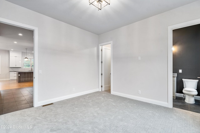 unfurnished bedroom featuring baseboards, carpet floors, and ensuite bath
