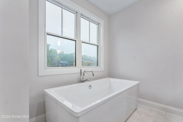 bathroom featuring marble finish floor, plenty of natural light, and baseboards