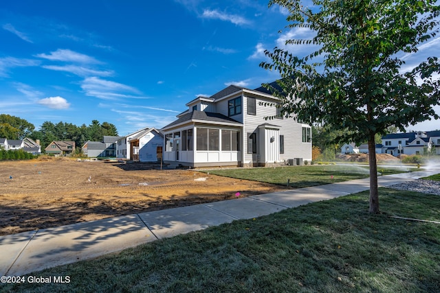 view of front facade featuring a front yard, a sunroom, and central AC