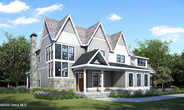 view of front of property with a front lawn, a porch, stone siding, and board and batten siding