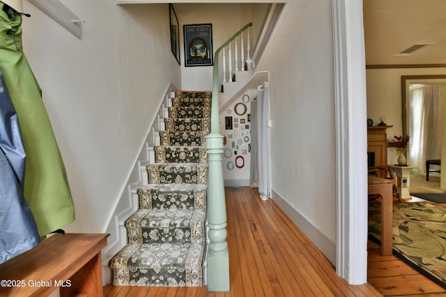 21 Andrews St, Saratoga Springs, NY 12866 - stairs with hardwood / wood-style floors, ornamental molding, baseboards, visible vents, and a fireplace