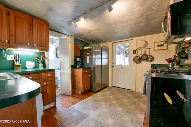 21 Andrews St, Saratoga Springs, NY 12866 - kitchen with light wood-style flooring, dark countertops, appliances with stainless steel finishes, and brown cabinets