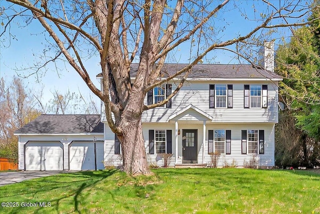 colonial house with an attached garage, a front lawn, driveway, and a chimney