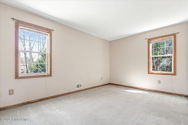 empty room with carpet floors, baseboards, and visible vents