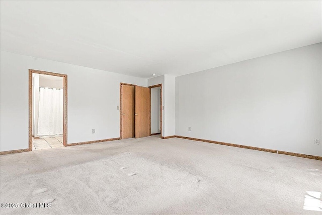unfurnished room with baseboards and light colored carpet