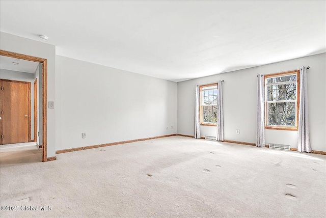 spare room featuring carpet floors, baseboards, and visible vents