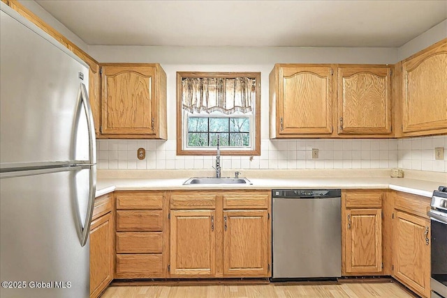 kitchen featuring a sink, decorative backsplash, stainless steel appliances, and light wood-style flooring