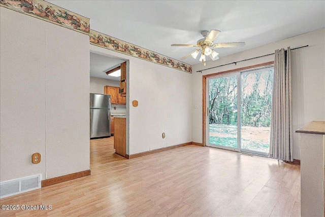empty room featuring baseboards, ceiling fan, visible vents, and light wood-style flooring