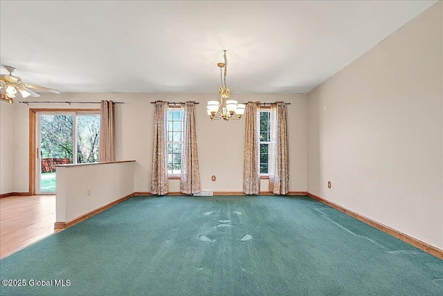 carpeted spare room with baseboards and ceiling fan with notable chandelier
