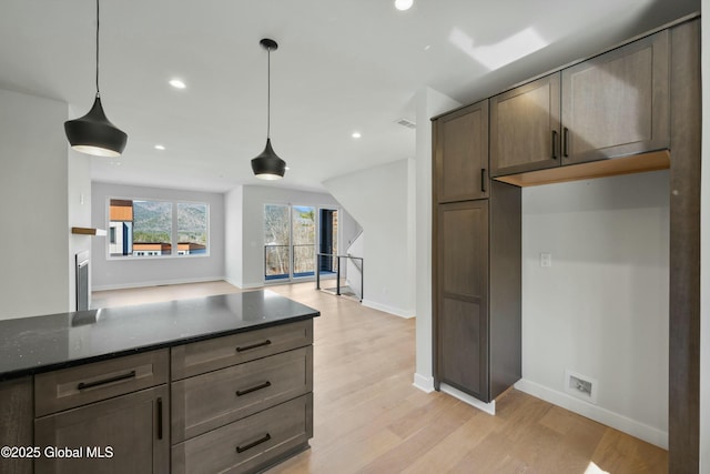 kitchen featuring light wood-style flooring, baseboards, recessed lighting, and dark stone counters