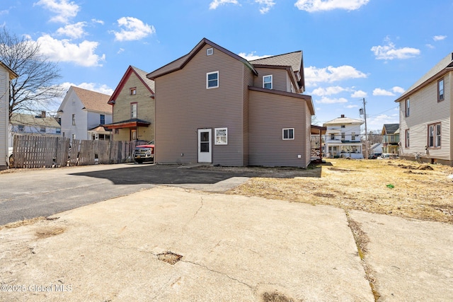 back of property featuring a residential view, driveway, and fence