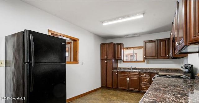 kitchen featuring baseboards, a sink, stainless steel electric stove, and freestanding refrigerator