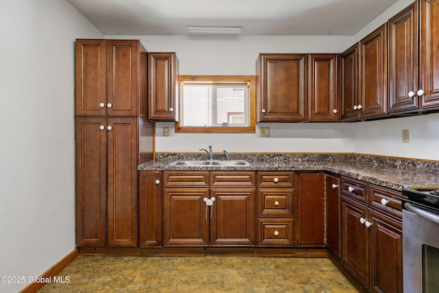 kitchen featuring electric range, a sink, dark countertops, and baseboards