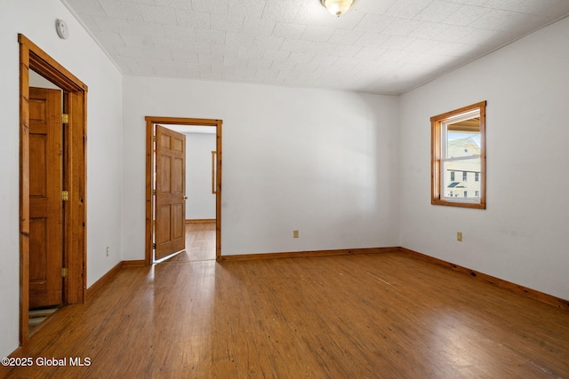 empty room with baseboards and wood finished floors