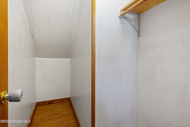 walk in closet with wood finished floors and vaulted ceiling