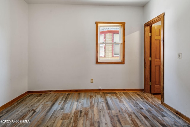 spare room with visible vents, baseboards, and wood finished floors