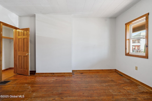spare room with wood-type flooring, baseboards, and visible vents