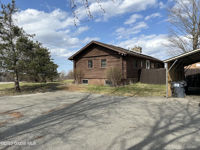 view of property exterior with log exterior, fence, and a chimney