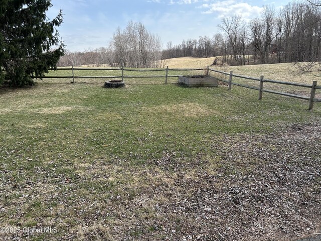 view of yard with fence and a rural view