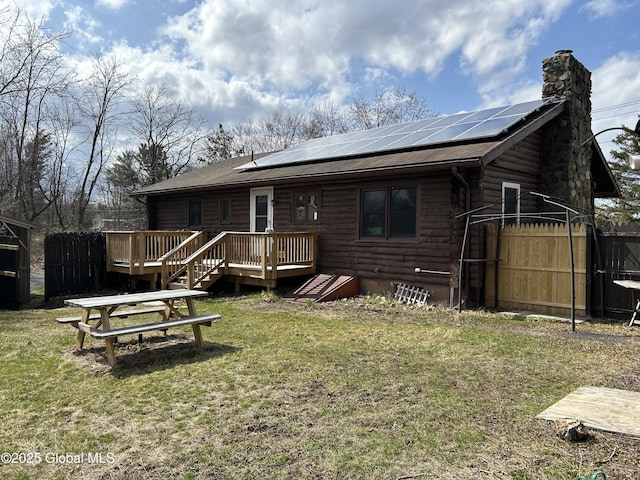 back of house featuring roof mounted solar panels, a yard, and a wooden deck