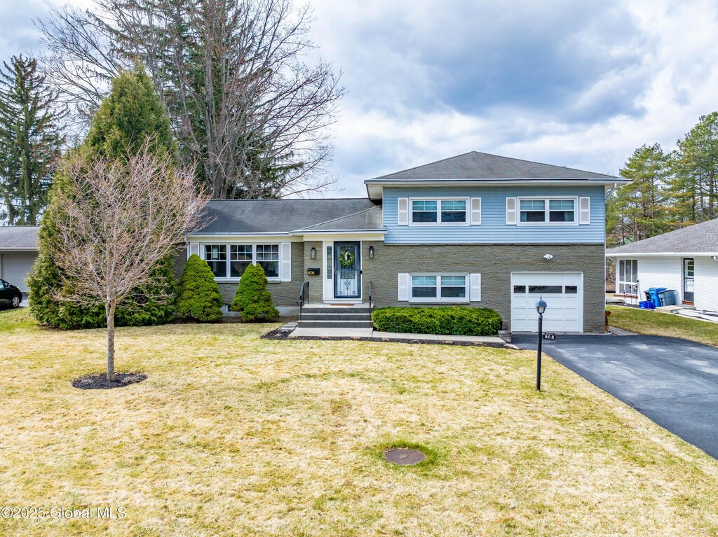808 Cortland St, Albany, NY 12203 - tri-level home featuring a front yard, a garage, and aphalt driveway