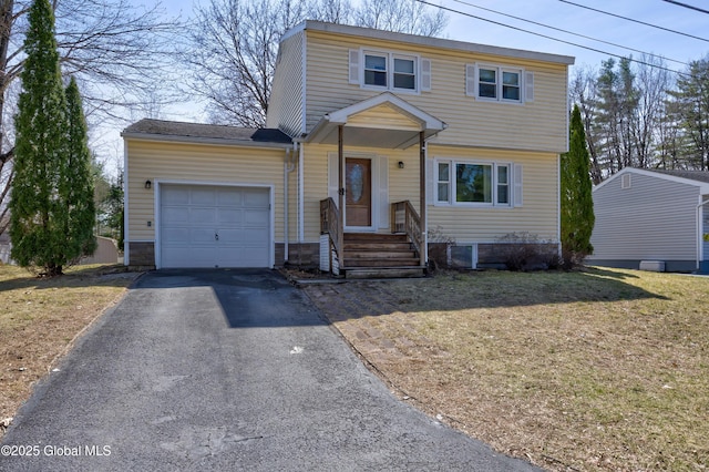 colonial-style house with aphalt driveway, a front lawn, and an attached garage