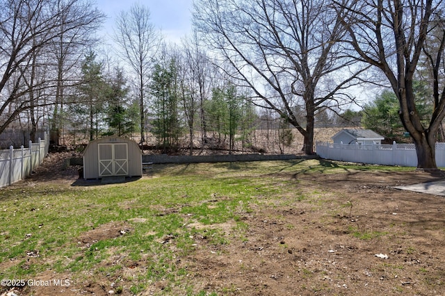 view of yard featuring a storage shed, fence, and an outbuilding