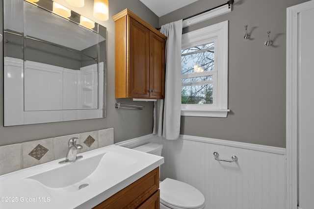 bathroom featuring toilet, vanity, and wainscoting