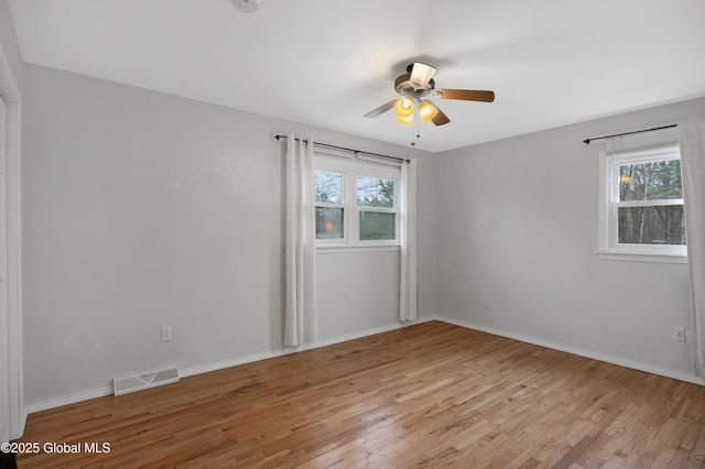 empty room featuring visible vents, light wood-style flooring, ceiling fan, and a healthy amount of sunlight