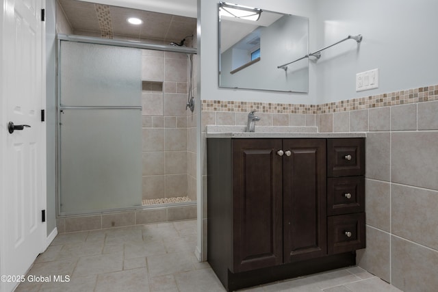 bathroom featuring a shower stall, vanity, and tile walls