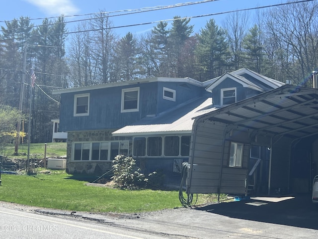 view of front of house featuring a detached carport, a front yard, driveway, and stone siding