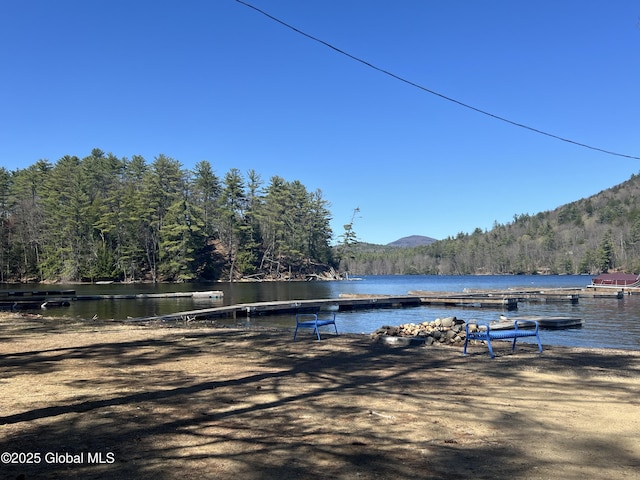 view of dock with a water and mountain view and a forest view