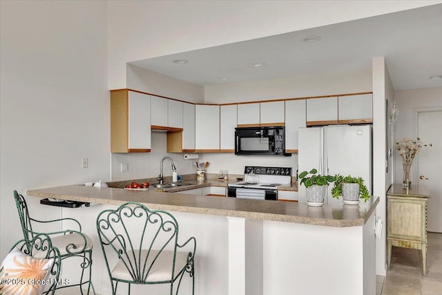 kitchen featuring a sink, light tile patterned flooring, white appliances, white cabinets, and a peninsula