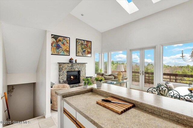 living room featuring a skylight, french doors, high vaulted ceiling, and light tile patterned floors